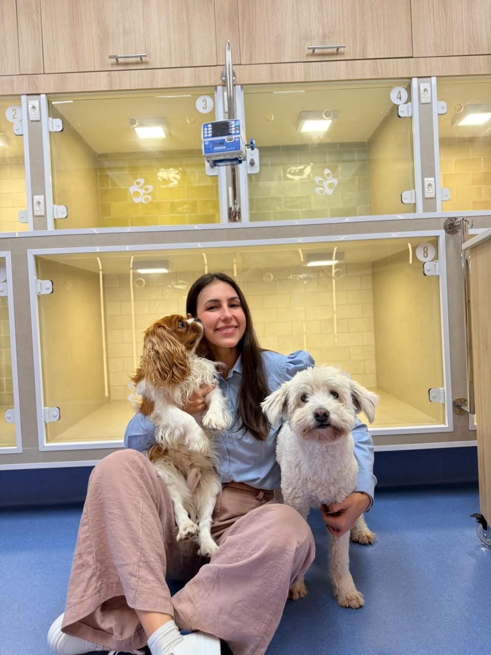 Ketlin Boff sentada com dois cães em frente às acomodações de internação da Alluvie.