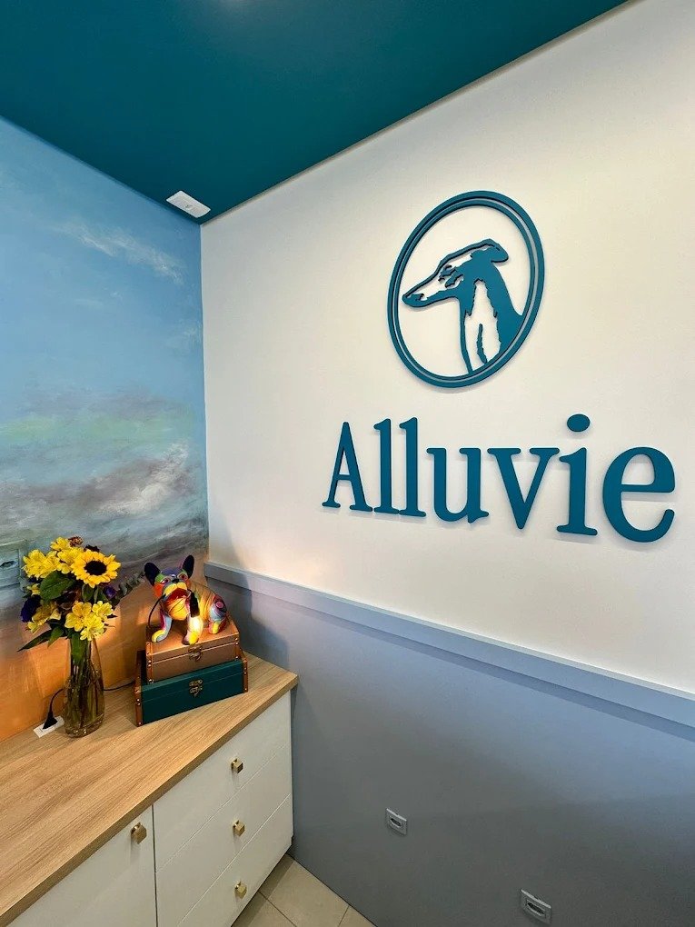 Detalhe da recepção com o logotipo da Alluvie na parede e arranjo de flores.